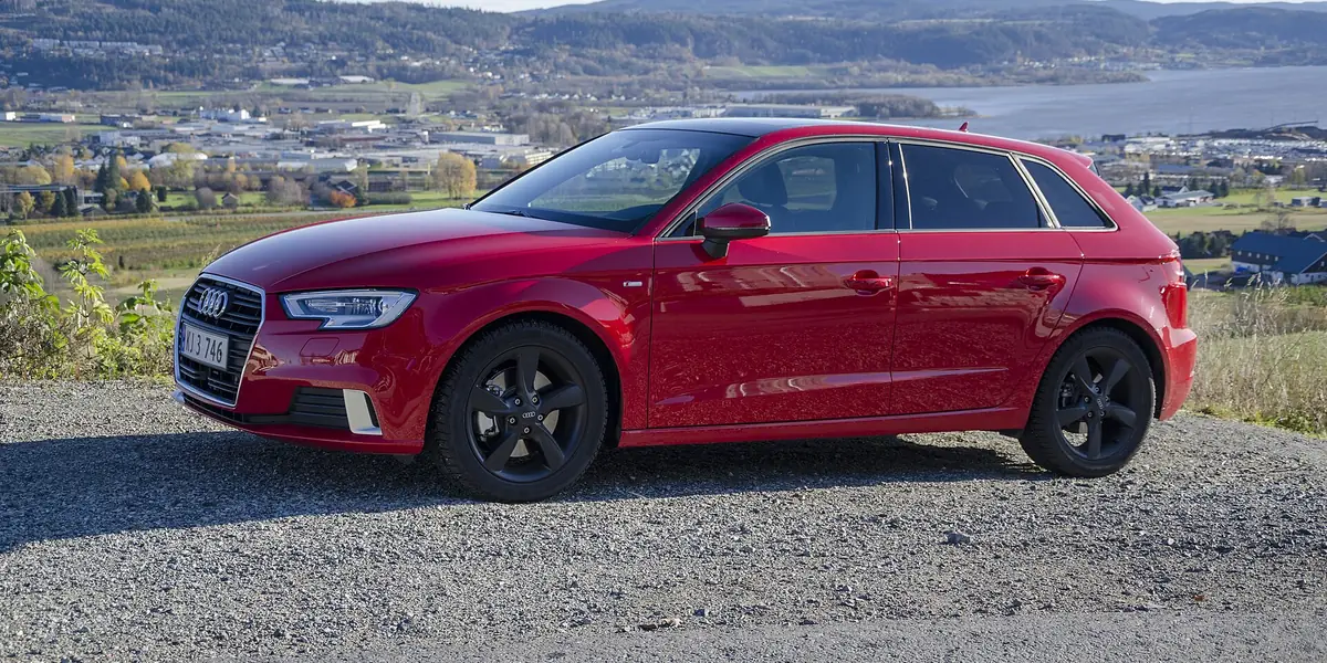 Een rode Audi A3 Sportback op een heuvel boven een fjord